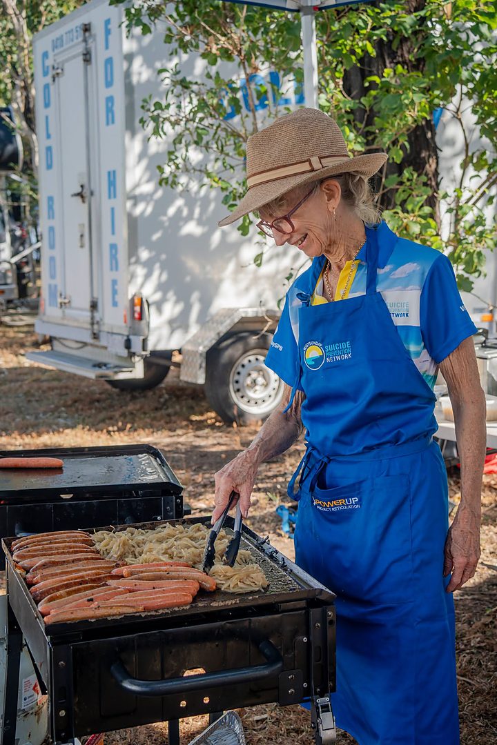A volunteer cooking sausages on the barbecue at the WSPN breakfast